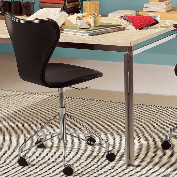 Syver kontorstol designet af Arne Jacobsen for Fritz Hansen i sort læder ved skrivebord på kontor