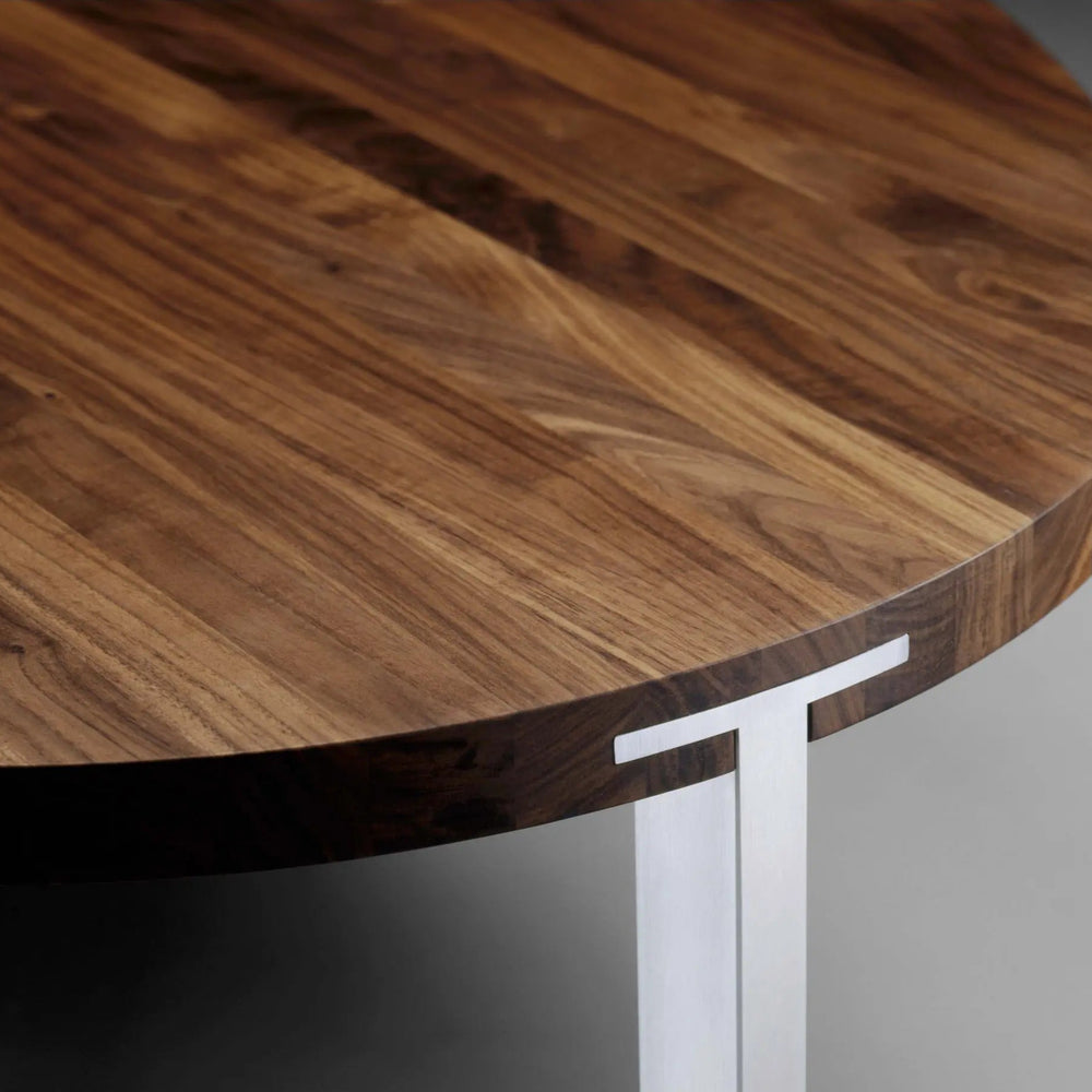 Rundt spisebord fra Naver Collection. Bordet har en bordplade af træ og bordben i rustfrit stål, som fås i forskellige farver.