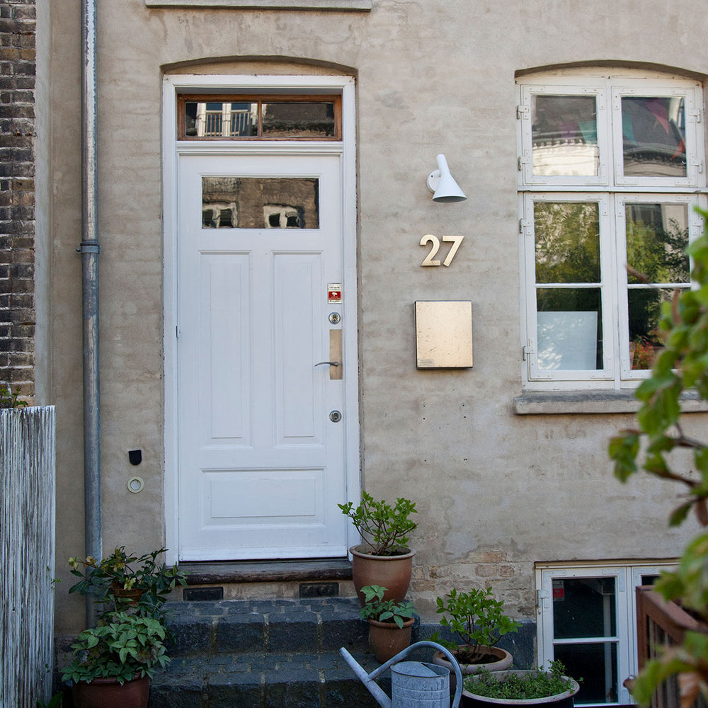 AJ 50 væglampe til udendørs brug designet Arne Jacobsen for Louis Poulsen i hvid på husmur ved hoveddør