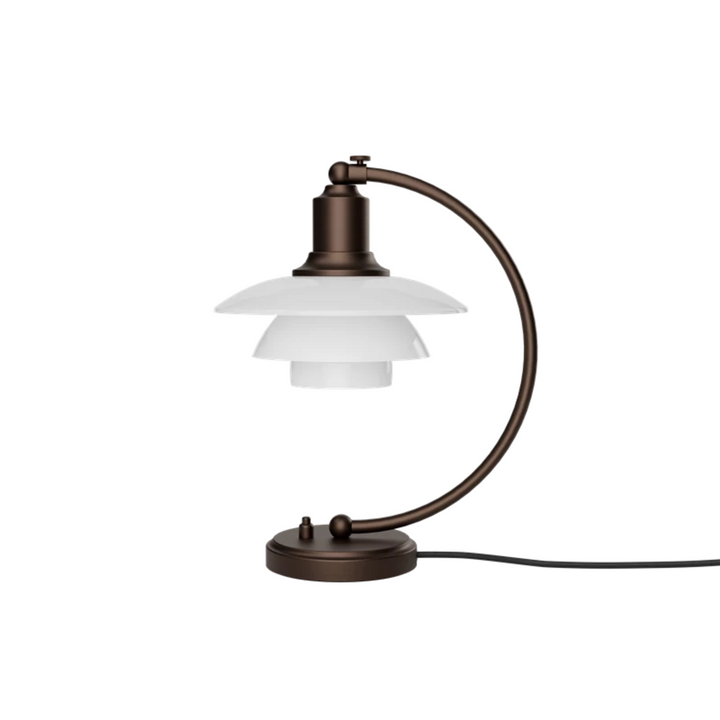 PH 2/2 Luna Aged Brass Opal Bordlampe i bruneret messing har Poul Henningsens karakteristiske treskærmssystem med skærme af mundblæst opalhvidt glas, der er blankt på ydersiden og sandblæst mat på undersiden. Det giver både et perfekt nedadrettet lys og et blødt, diffust lys rundt om lampen, som skaber stemning.