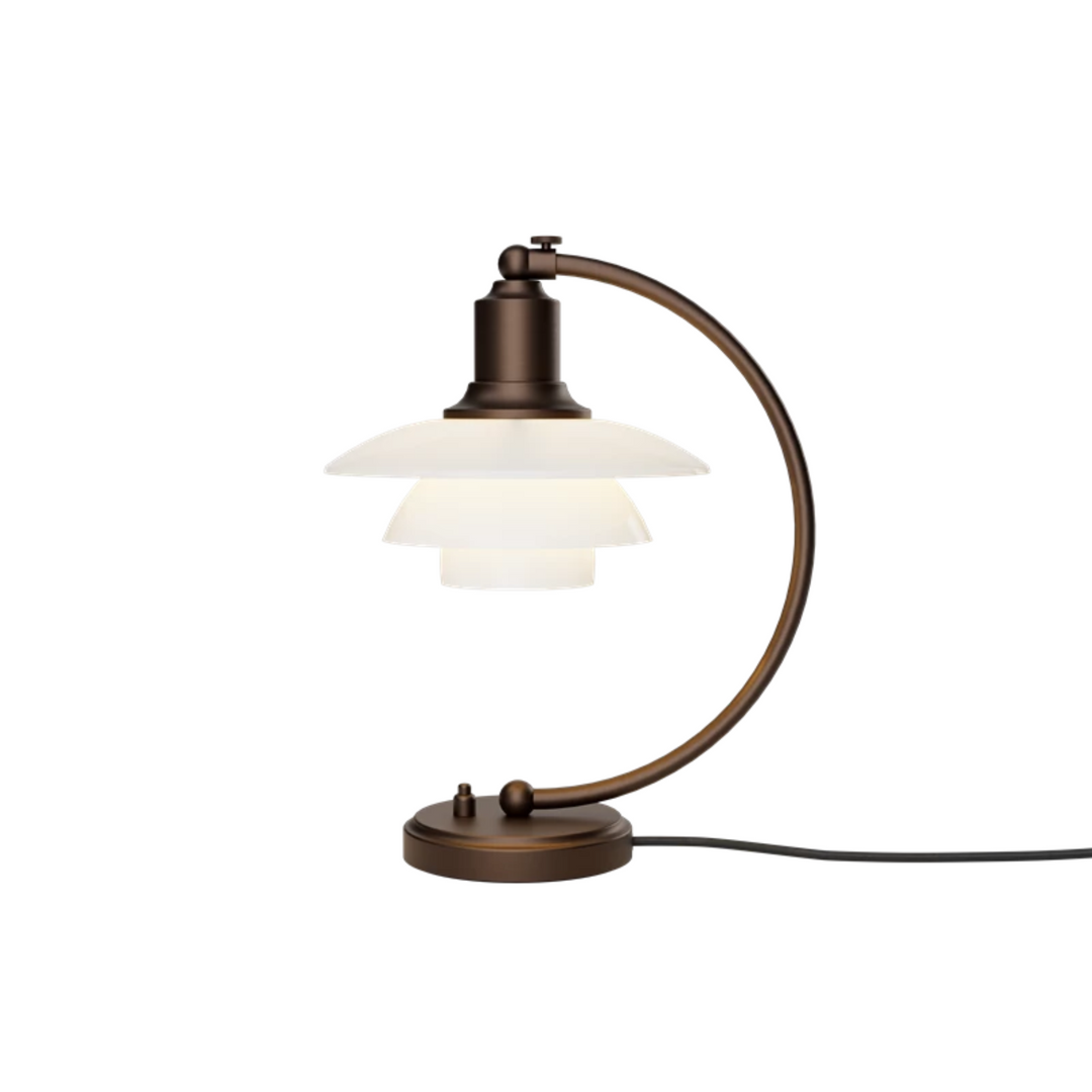 PH 2/2 Luna Aged Brass Opal Bordlampe i bruneret messing har Poul Henningsens karakteristiske treskærmssystem med skærme af mundblæst opalhvidt glas, der er blankt på ydersiden og sandblæst mat på undersiden. Det giver både et perfekt nedadrettet lys og et blødt, diffust lys rundt om lampen, som skaber stemning.